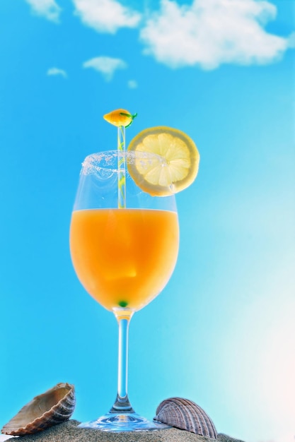ビーチの砂の上の青い空のオレンジジュースカクテルに対して,テーブル上の飲み物のクローズアップ