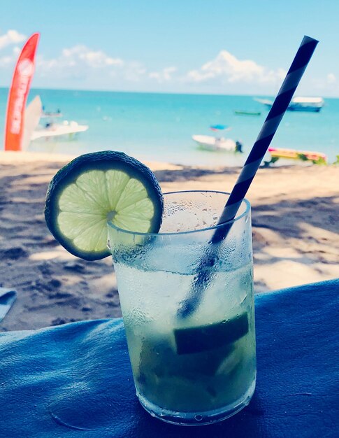 Photo close-up of drink on table against sea