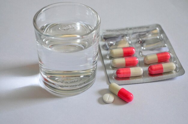 Foto close-up di acqua potabile e farmaci su sfondo bianco