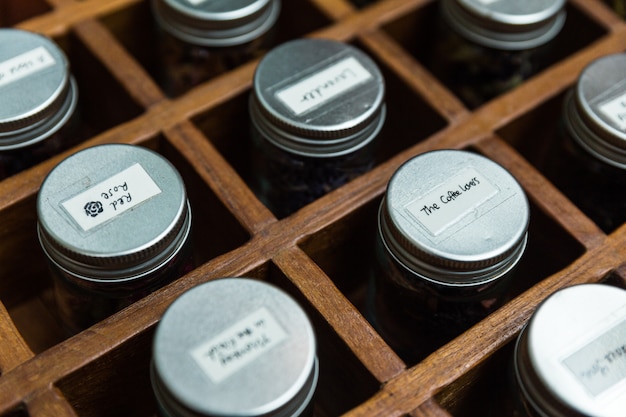 Close-up dry flower tea glass bottles with aluminium lid inside wooden box.