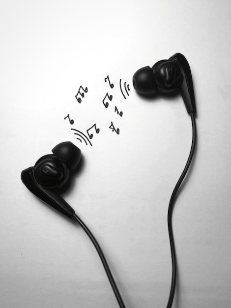 Foto close-up di cuffie in-ear con note musicali su sfondo bianco