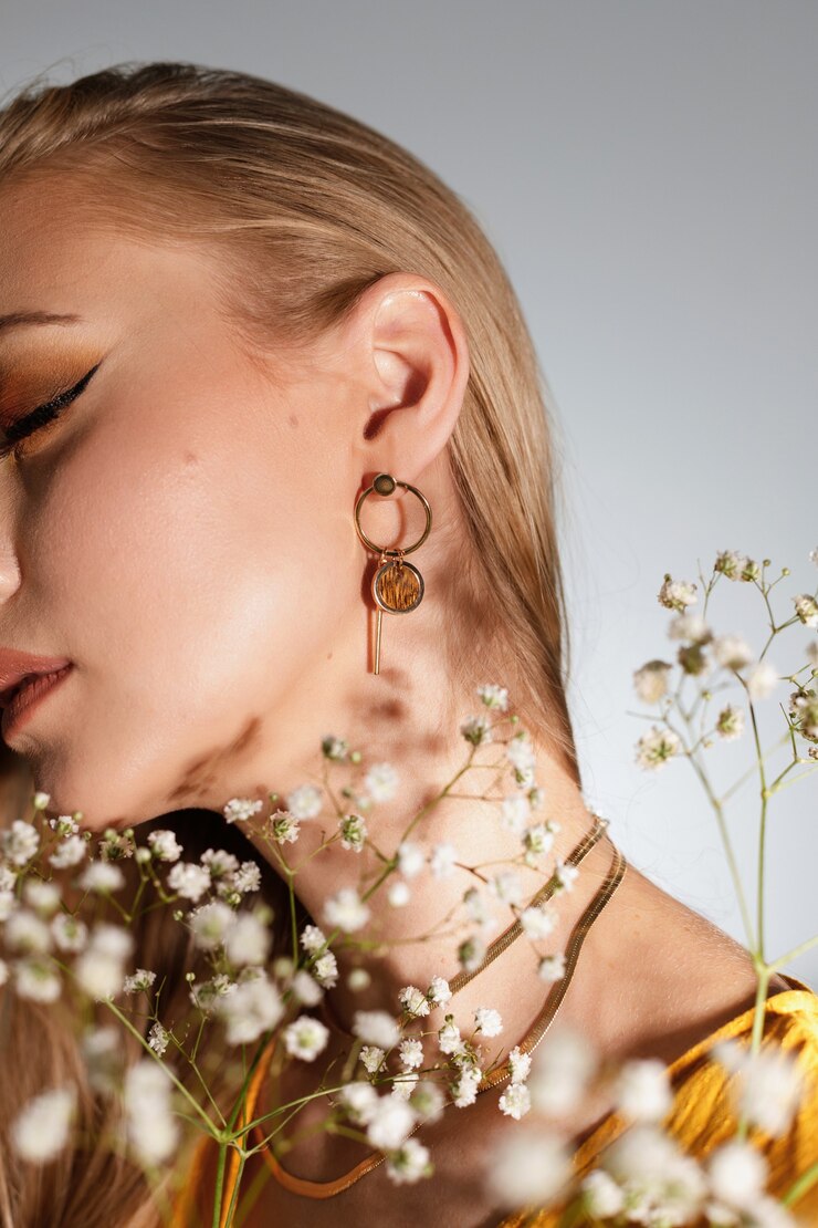 Photo close-up of earrings on the ear of a blonde model with a bouquet of flowers. fashion blogger