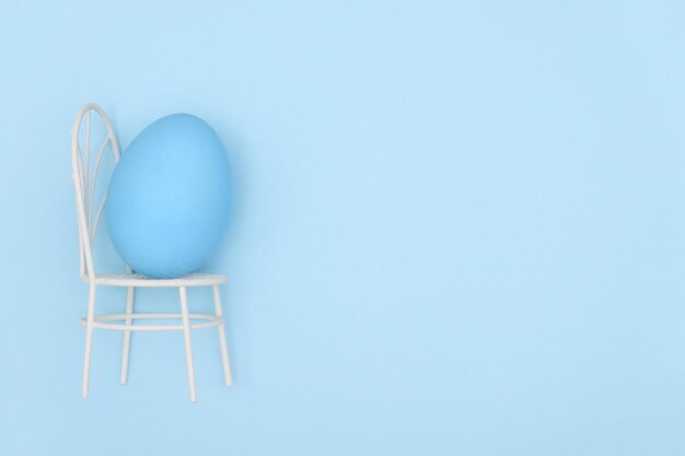 Photo close-up of easter egg on small chair over blue background