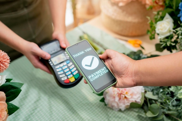 Close up of easy payment by credit card or smartphone application Greenhouse workers selling pottered flowersContactless payment with credit card customer at counter using QR code contactless payment