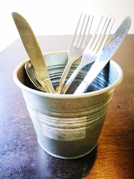 Photo close-up of eating utensils in container on table