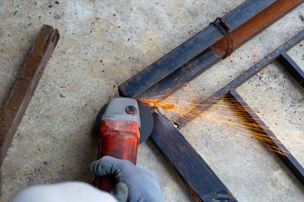 Close-up, een man aan het werk met een haakse slijper. Reparatie van ijzeren poort