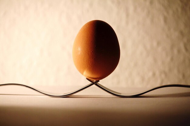 Close-up of egg over forks on table