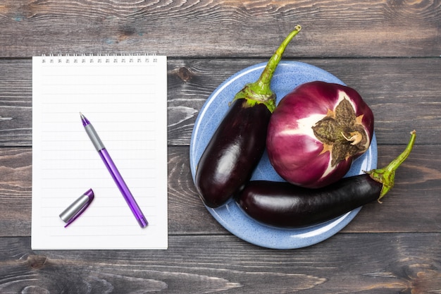 Photo close-up of eggplants on a blue plate and a notebook