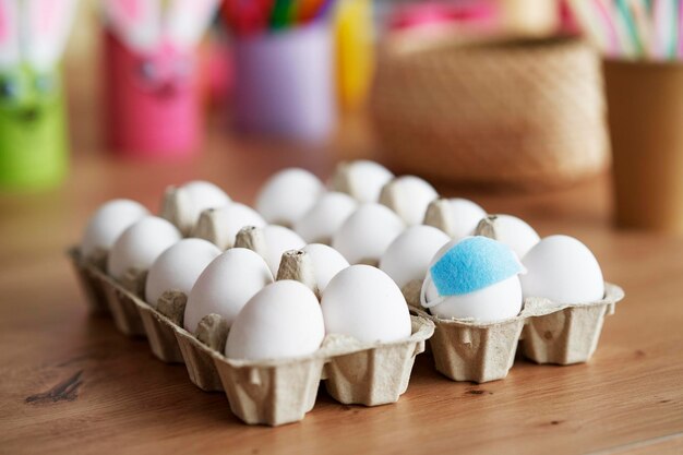 Close up eggs with face masks in a cardboard box