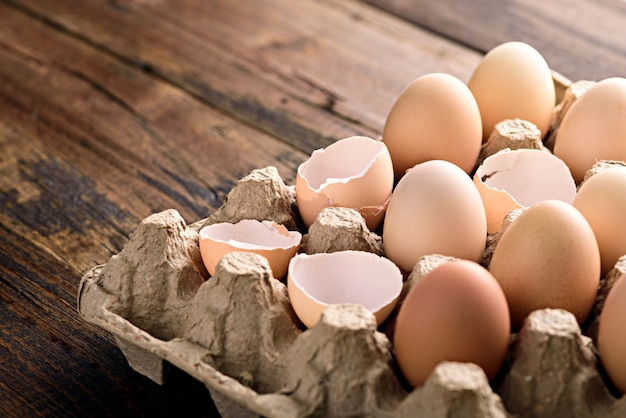 Close up eggs with shells in eco-friendly cardboard box on brown background