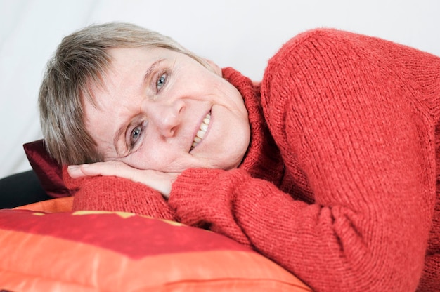 Foto close up einer alteren frau auf der seite liegend und in die kamera lachelnd vor weien hintergrund