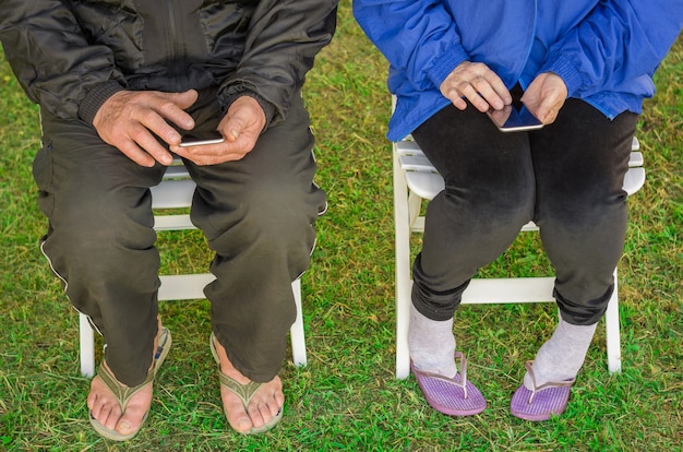 Close up of elderly couple sitting using smartphone