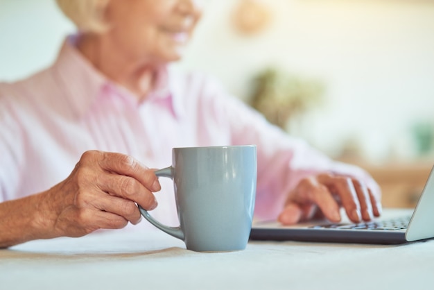 Primo piano di una signora anziana che tiene in mano una tazza di caffè