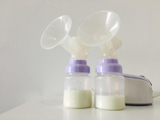 Close-up of electric breast pumps on table against white wall