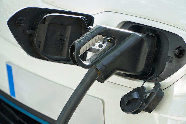 Close up of an electric car connected to the power station nozzle