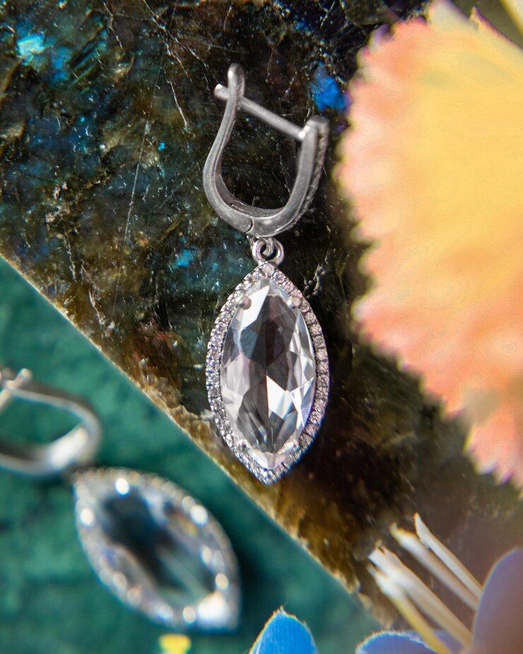 Close up of elegant diamond earrings lying on colorful stone surface