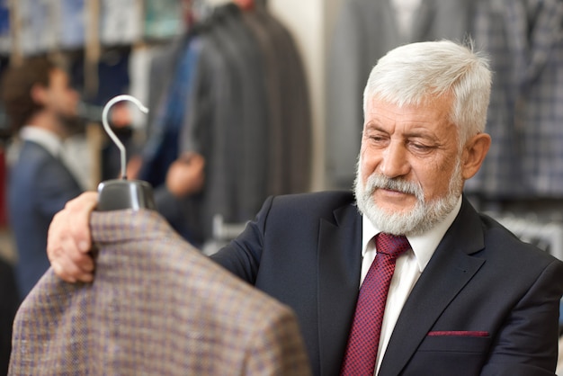 Close up of elegant older client holding brown jacket.