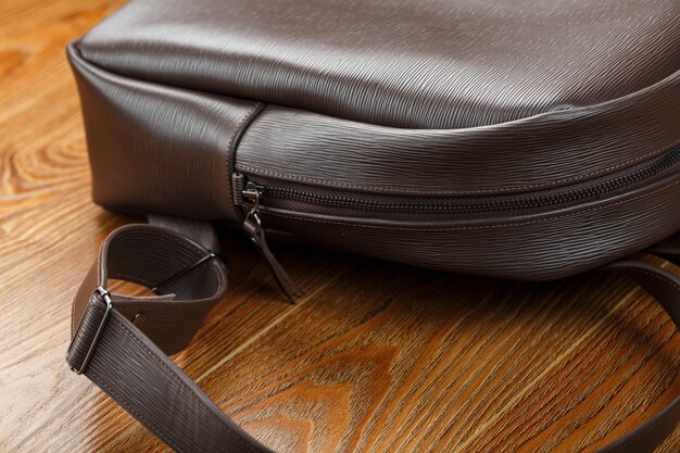 Close-up elements and details of the Backpack made of brown genuine leather on a wooden table.