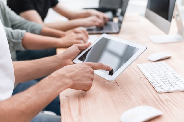 Foto avvicinamento. il dipendente utilizza un tablet digitale sul posto di lavoro