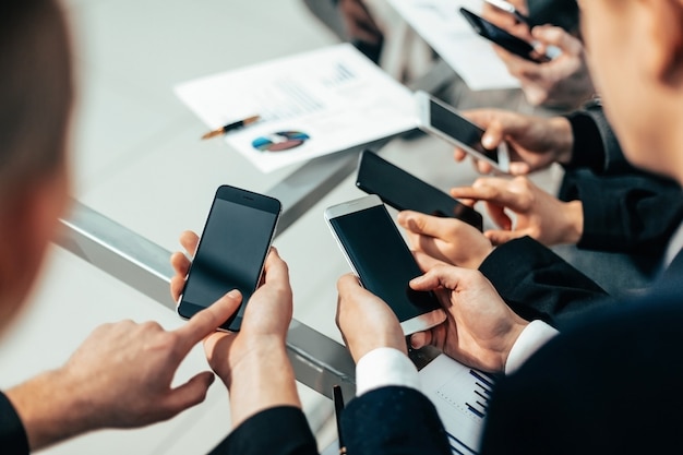 Close up . employees with smartphones analyzing financial data. people and technology