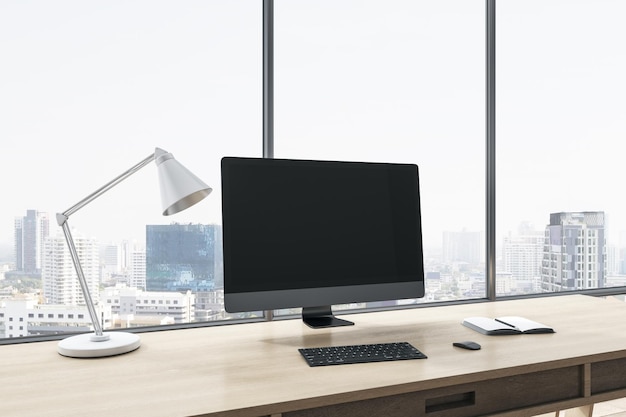 Close up of empty computer display on wooden office desktop\
with objects lamp and supplies on panoramic window and city view\
background mock up 3d rendering