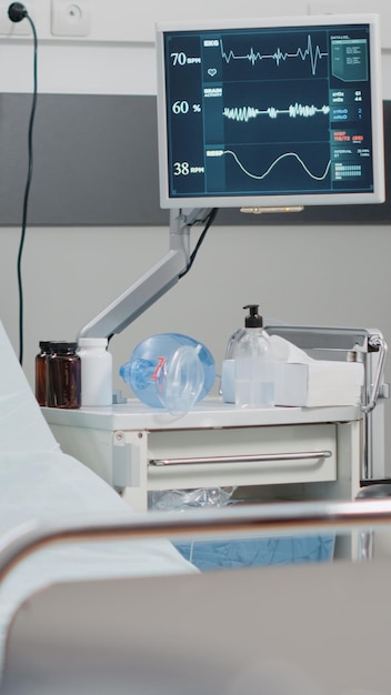 Close up of empty hospital ward bed with medical equipment. emergency room with reanimation tools for healthcare, heart rate monitor and oxygen tube. space for intensive care recovery