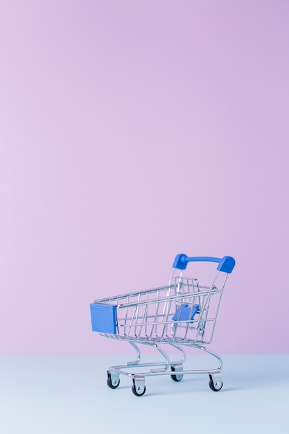 Close-up of an empty shopping cart in front of pink background