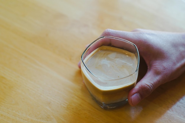 Close-up en selectieve focushand met vuil koffieglas op houten tafel in café.