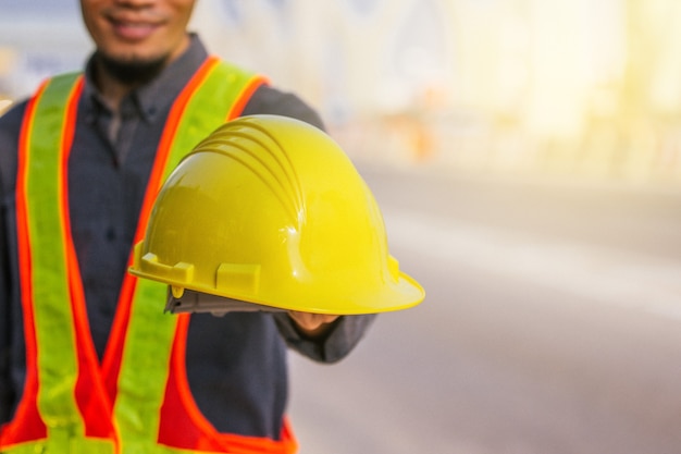 Close up engineer hold hard hat site construction background