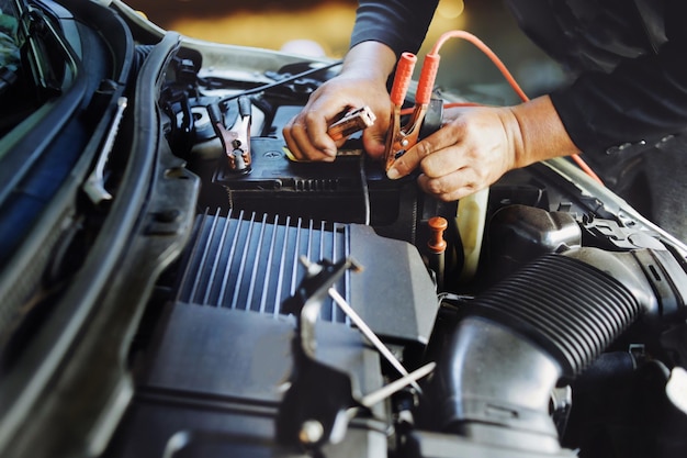 Close up Engineering hands fix And check battery of car engine working at garage