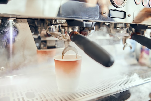 Close-up of espresso pouring from coffee machine. Professional coffee brewing.