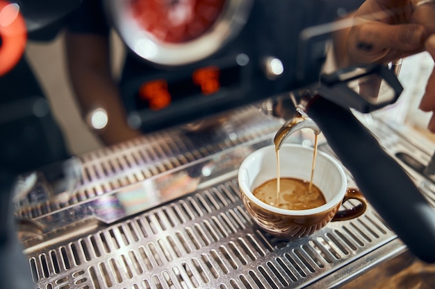 Close-up of espresso pouring from coffee machine. Professional coffee brewing.