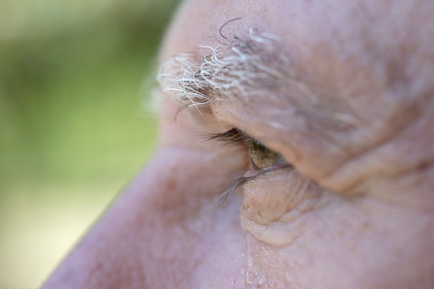 Close up eye of caucasian old man. Portrait of old man outdoors. Caucasian male face background, close up eyes, macro