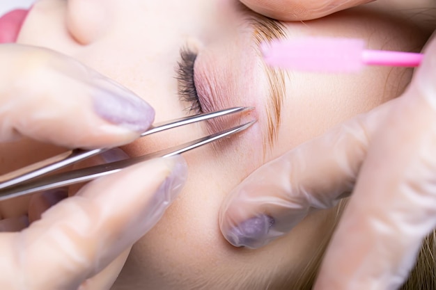 Close-up of the eyebrows after the lamination procedure, the master tweezers to pluck the hairs