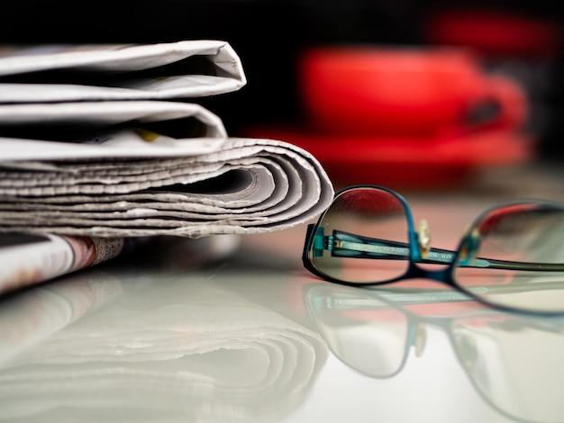 Close-up of eyeglasses by newspaper on table