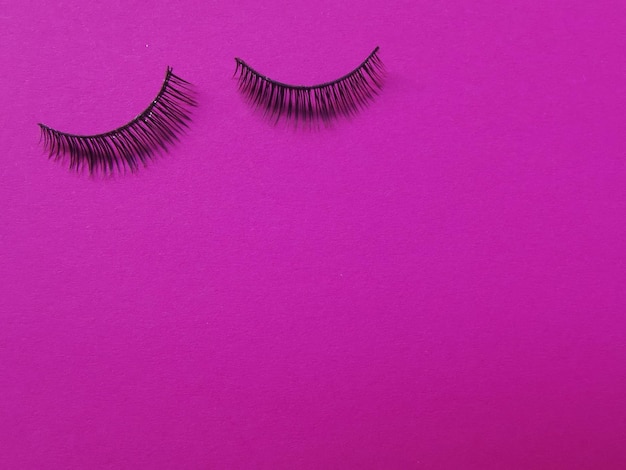 Close-up of eyelashes against pink background