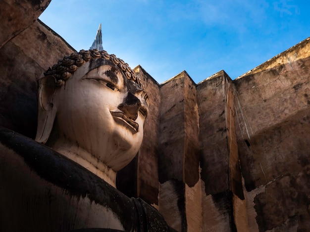 태국의 유네스코 세계 문화 유산인 수코타이 역사 공원(Sukhothai Historical Park)의 유명한 랜드마크인 왓 스리 첨 사원(Wat Sri Chum Temple)의 오래된 교회 내부에 있는 고대 큰 불상의 클로즈업 얼굴.