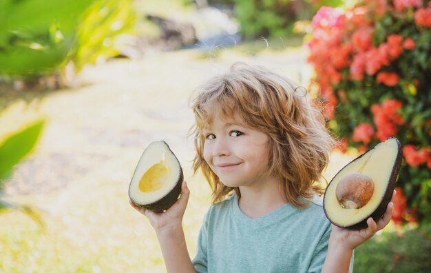 Close up face of kid with half an avocado in her handat tropical garden healthy kids avocado food co