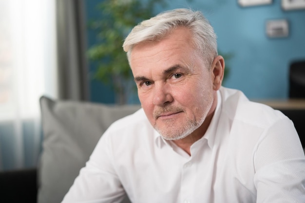 Close up face portrait of healthy cheerful mature grayhaired businessman smiling to the camera