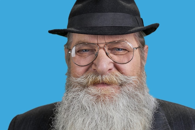 Foto primo piano del viso dell'uomo anziano dalla barba lunga isolato sul blu