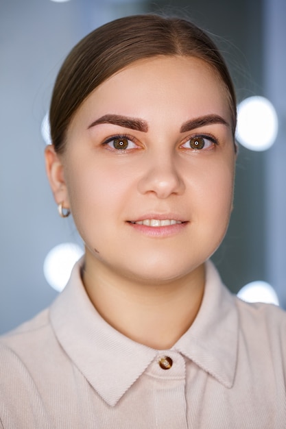 A close-up of the face of a young woman who has just had a permanent eyebrow tattoo done.