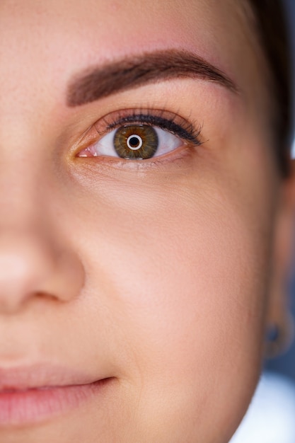 A close-up of the face of a young woman who has just had a permanent eyebrow tattoo done.