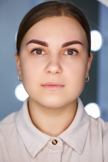 A close-up of the face of a young woman who has just had a permanent eyebrow tattoo done.