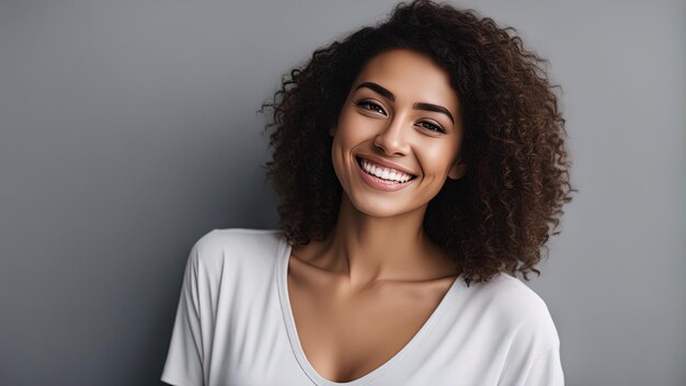 Close up face of young woman with beautiful smile isolated on grey wall with copy space Successful multiethnic girl Woman looking at camera against gray wall with a big whitening teeth smile