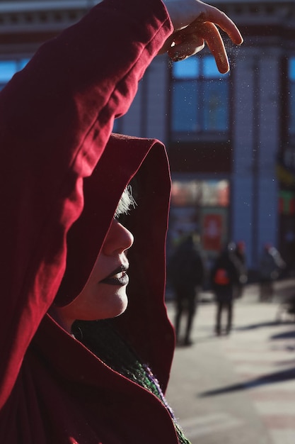 Close up fantasy woman in red hood sprinkling pixie dust above head portrait picture