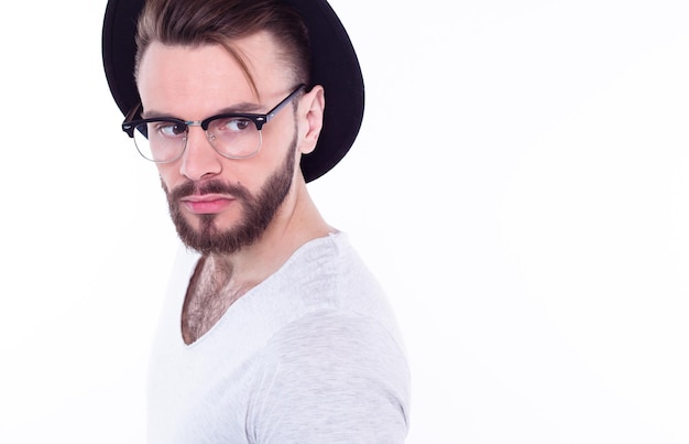 Close up fashion portrait of young bearded man Smiling hipster guy Handsome man in stylish hat Brutal bearded boy in trendy glasses