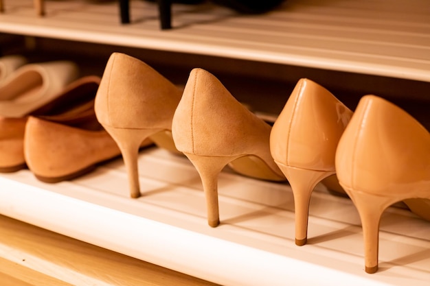 세련된 여성 하이힐 가죽 신발을 닫으세요. 상점의 선반에 나란히 서 있는 베이지색 신발 컬렉션 쇼핑 개념