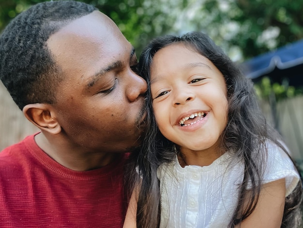 Close-up of father embracing daughter sitting outdoors