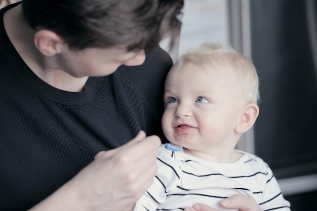 close-up of father feeding food to baby boy at home