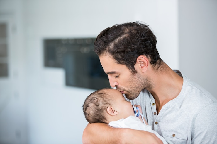 Photo close-up of father kissing baby 